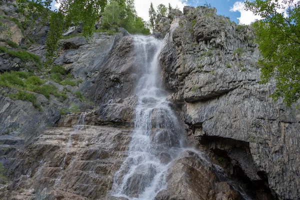 岩や緑の木々の間の小さな川の上の高い滝 — ストック写真