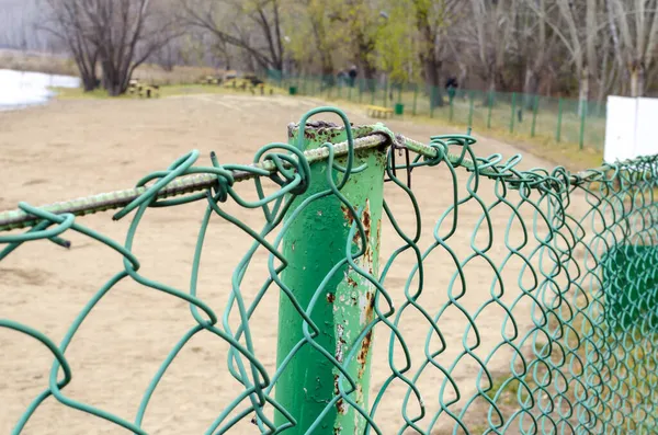 漆成绿色的金属网 围栏围住了一个大森林湖的地盘 — 图库照片