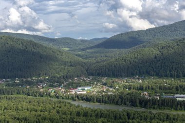 Mavi gökyüzünde beyaz kabarık bulutlar ve dağ zirveleri