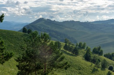 Mavi gökyüzünde beyaz kabarık bulutlar ve dağ zirveleri