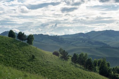 Mavi gökyüzünde beyaz kabarık bulutlar ve dağ zirveleri