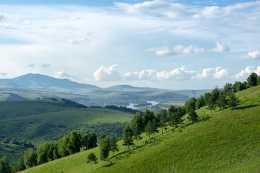 Mavi gökyüzünde beyaz kabarık bulutlar ve dağ zirveleri