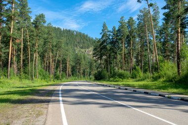 Dağ tepeleri arasında asfalt yol. Açık güneşli yaz günü