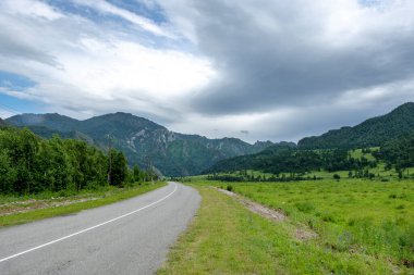 Dağ tepeleri arasında asfalt yol. Sıcak yaz günü