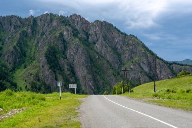 Dağ tepeleri arasında asfalt yol. Sıcak yaz günü
