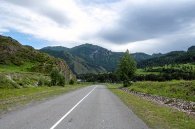 Dağ tepeleri arasında asfalt yol. Sıcak yaz günü