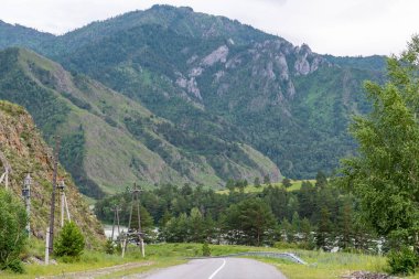 Dağ tepeleri arasında asfalt yol. Sıcak yaz günü