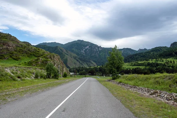 Dağ tepeleri arasında asfalt yol. Sıcak yaz günü