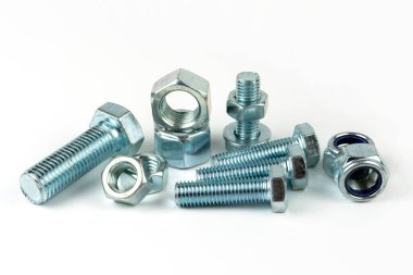 Gümüş metal cıvatalı büyük metal fındıklar. Beyaz arka planda yakın plan. Bir grup somun ve cıvata.