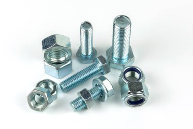 Gümüş metal cıvatalı büyük metal fındıklar. Beyaz arka planda yakın plan. Bir grup somun ve cıvata.