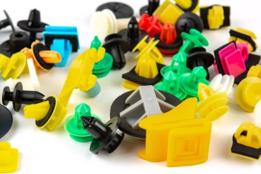 Araba için plastik renkli klipslerin yakın plan çekimi. Soyut arkaplan. Beyaz arka planda izole edilmiş plastik perçinler. Otomatik plastik kelepçeler. Yalıtımlı şarjör veya otomatik plastik toka