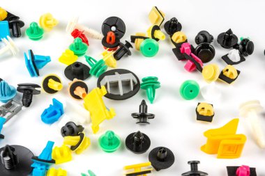 Araba için plastik renkli klipslerin yakın plan çekimi. Soyut arkaplan. Beyaz arka planda izole edilmiş plastik perçinler. Otomatik plastik kelepçeler. Yalıtımlı şarjör veya otomatik plastik toka