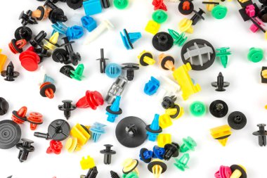 Araba için plastik renkli klipslerin yakın plan çekimi. Soyut arkaplan. Beyaz arka planda izole edilmiş plastik perçinler. Otomatik plastik kelepçeler. Yalıtımlı şarjör veya otomatik plastik toka
