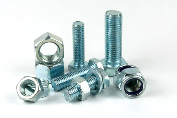 Gümüş metal cıvatalı büyük metal fındıklar. Beyaz arka planda yakın plan. Bir grup somun ve cıvata.