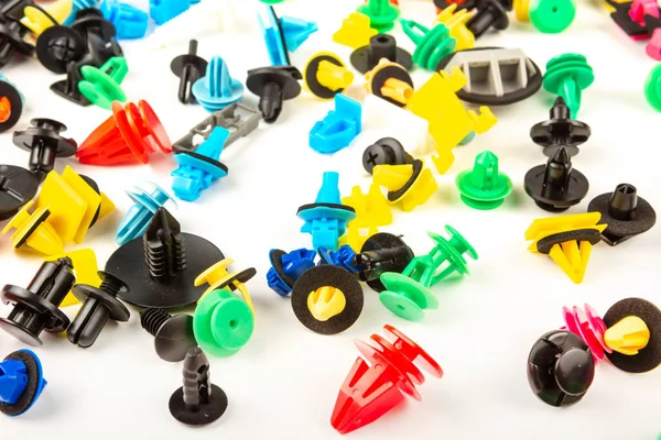 Araba için plastik renkli klipslerin yakın plan çekimi. Soyut arkaplan. Beyaz arka planda izole edilmiş plastik perçinler. Otomatik plastik kelepçeler. Yalıtımlı şarjör veya otomatik plastik toka