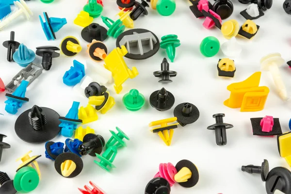 Araba için plastik renkli klipslerin yakın plan çekimi. Soyut arkaplan. Beyaz arka planda izole edilmiş plastik perçinler. Otomatik plastik kelepçeler. Yalıtımlı şarjör veya otomatik plastik toka