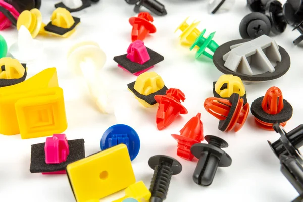 Araba için plastik renkli klipslerin yakın plan çekimi. Soyut arkaplan. Beyaz arka planda izole edilmiş plastik perçinler. Otomatik plastik kelepçeler. Yalıtımlı şarjör veya otomatik plastik toka