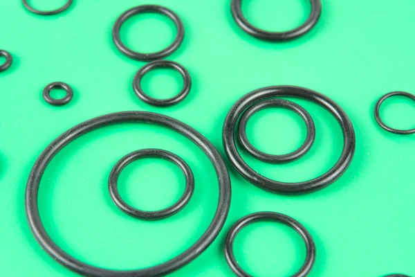 Yeşil arka planda siyah hidrolik ve pnömatik O halkaları farklı boyutlarda. Hidrolik bağlantılar için contalar mühürleniyor. Su tesisatı için lastik kaplama halkaları..