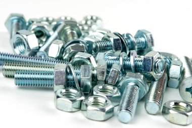 A large group of silver fasteners for fastening structures. Bolts and nuts with washers close-up on a white background.