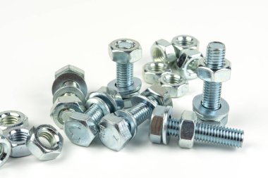 A large group of silver fasteners for fastening structures. Bolts and nuts with washers close-up on a white background.