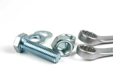 A small group of silver fasteners for fastening structures. Bolts and nuts with washers close-up on a white background. Several wrenches.