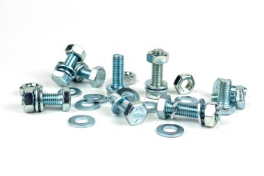 Beyaz arka planda vidaları ve fındıkları olan birkaç metal cıvata. yakın plan