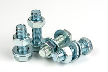 Beyaz arka planda vidaları ve fındıkları olan birkaç metal cıvata. yakın plan