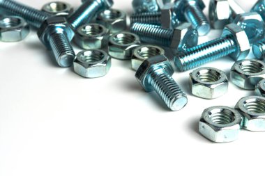 Beyaz arka planda vidaları ve fındıkları olan birkaç metal cıvata. yakın plan