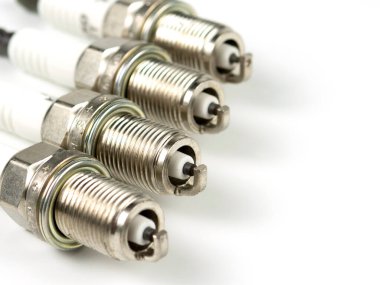 Beyaz arka planda yeni bir buji, izole edilmiş. Otomobil motoru yakın çekimi için dört kıvılcım eklentisi grubu