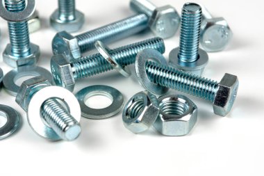 Metal cıvatalar ve fındıklar. Yuvarlak temizleyiciler beyaz arka planda.