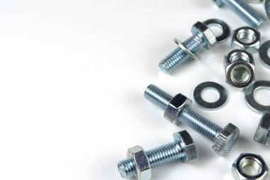 Metal cıvatalar ve fındıklar. Beyaz arka planda yuvarlak temizleyiciler var. Boşluğu kopyala