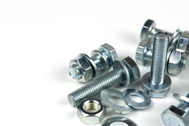 Metal cıvatalar ve fındıklar. Beyaz arka planda yuvarlak temizleyiciler var. Boşluğu kopyala