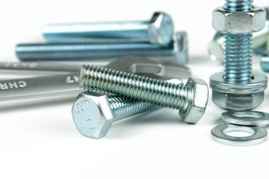 Beyaz arka planda yeni bir tamir aleti, cıvatalar ve fındıklar. Sürgülü fındıkları sıkılaştırarak başlıklı bir bağlantıyı bağlamak için araç