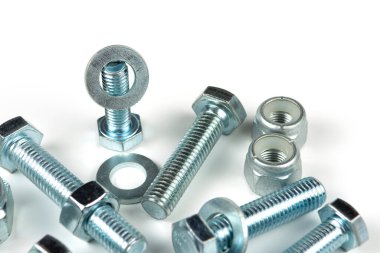 Metal cıvatalar ve fındıklar. Beyaz arka planda yuvarlak temizleyiciler var. Boşluğu kopyala