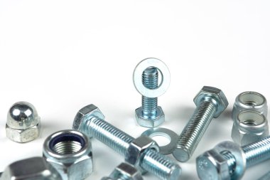 Metal cıvatalar ve fındıklar. Beyaz arka planda yuvarlak temizleyiciler var. Boşluğu kopyala