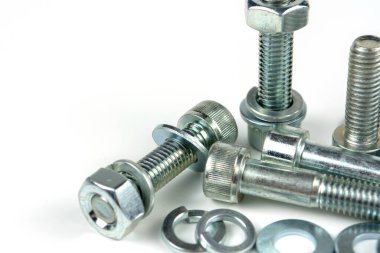 Metal cıvatalar ve fındıklar. Yuvarlak temizleyiciler beyaz arka planda.