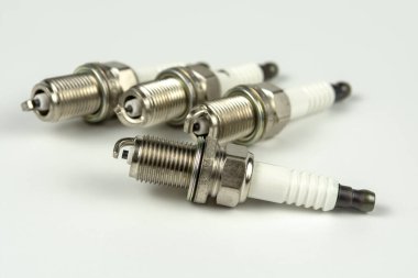 Beyaz arka planda yeni bir buji, izole edilmiş. Otomobil motoru yakın çekimi için dört kıvılcım eklentisi grubu