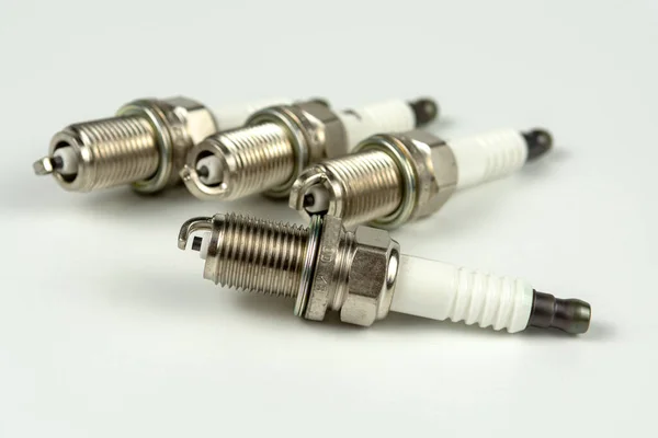 Beyaz arka planda yeni bir buji, izole edilmiş. Otomobil motoru yakın çekimi için dört kıvılcım eklentisi grubu