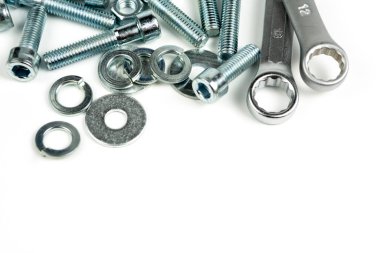 Beyaz arka planda fındıklı ve anahtarlı birkaç gümüş renkli metal cıvata. Boşluğu kapat ve kopyala