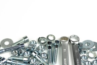 Beyaz arka planda fındıklı ve anahtarlı birkaç gümüş renkli metal cıvata. Boşluğu kapat ve kopyala