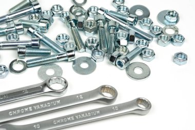 Beyaz arka planda fındıklı ve anahtarlı birkaç gümüş renkli metal cıvata. Boşluğu kapat ve kopyala