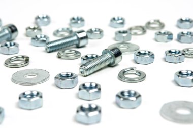 Beyaz arka planda fındıklı birkaç gümüş metal cıvata. soyut arkaplan, yakın plan
