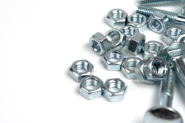 Beyaz arka planda fındıklı birkaç gümüş metal cıvata. Boşluğu kapat ve kopyala