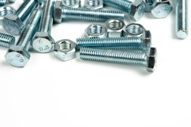 Beyaz arka planda fındıklı birkaç gümüş metal cıvata. Boşluğu kapat ve kopyala