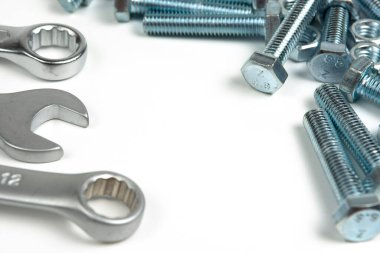 Beyaz arka planda fındıklı ve anahtarlı birkaç gümüş renkli metal cıvata. Boşluğu kapat ve kopyala