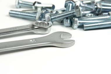 Beyaz arka planda fındıklı ve anahtarlı birkaç gümüş renkli metal cıvata. Boşluğu kapat ve kopyala