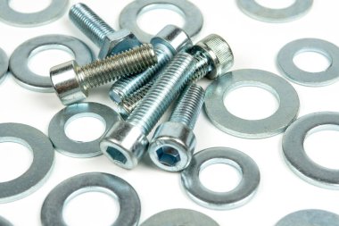 Beyaz arka planda gümüş renkli birkaç metal yıkama ve cıvata var. yakın plan