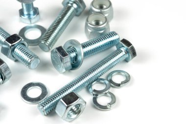 Metal cıvatalar ve fındıklar. Beyaz arka planda yuvarlak temizleyiciler var. Boşluğu kopyala