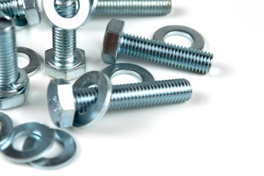 Metal cıvatalar ve fındıklar. Beyaz arka planda yuvarlak temizleyiciler var. Boşluğu kopyala