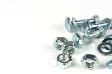 Metal cıvatalar ve fındıklar. Beyaz arka planda yuvarlak temizleyiciler var. Boşluğu kopyala